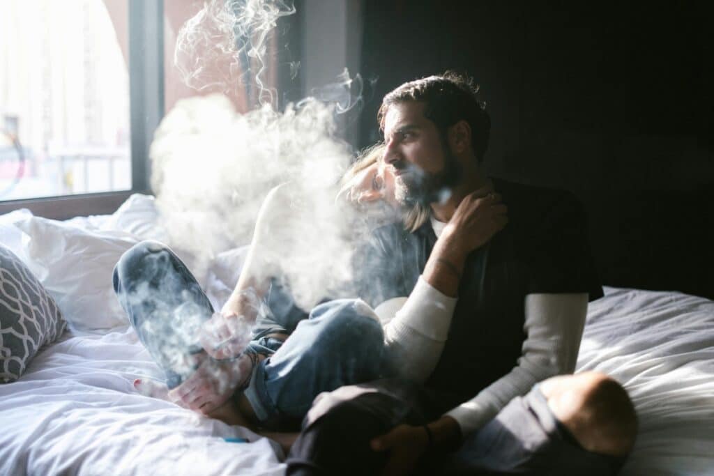 two people smoking a joint on a bed